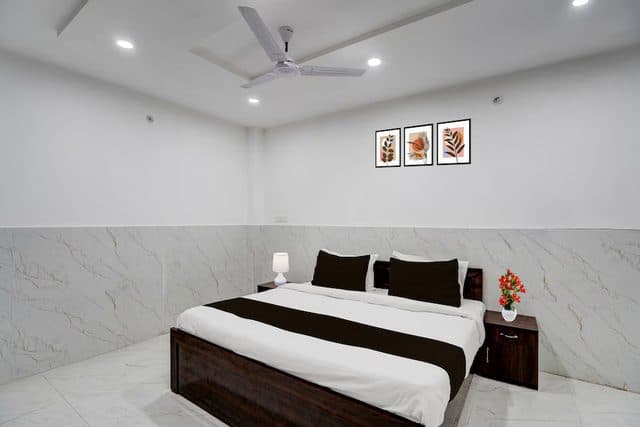 Bright, clean guest room with a made-up double bed and framed wall art at Metro Club & Guest House, Lucknow
